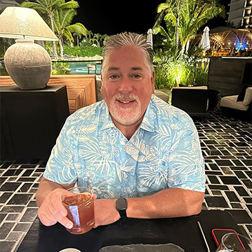 A man in a tropical bar with a cocktail