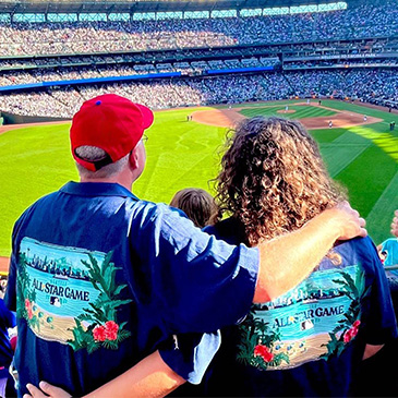 Fans at a baseball game wearing Tommy Bahama camp shirts