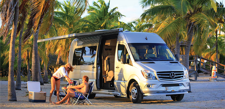 couple sitting in Tommy Bahama outdoor chairs on a beach with Airstream Van